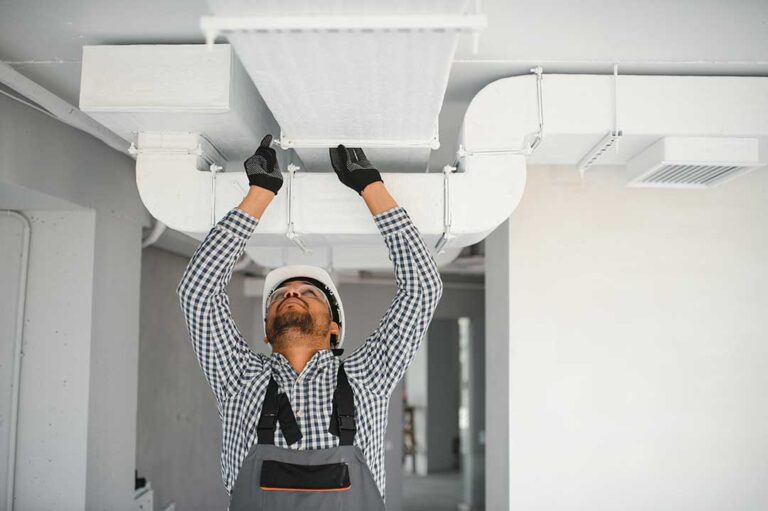 A person adjusting a digital home thermostat set between heating and cooling modes.
